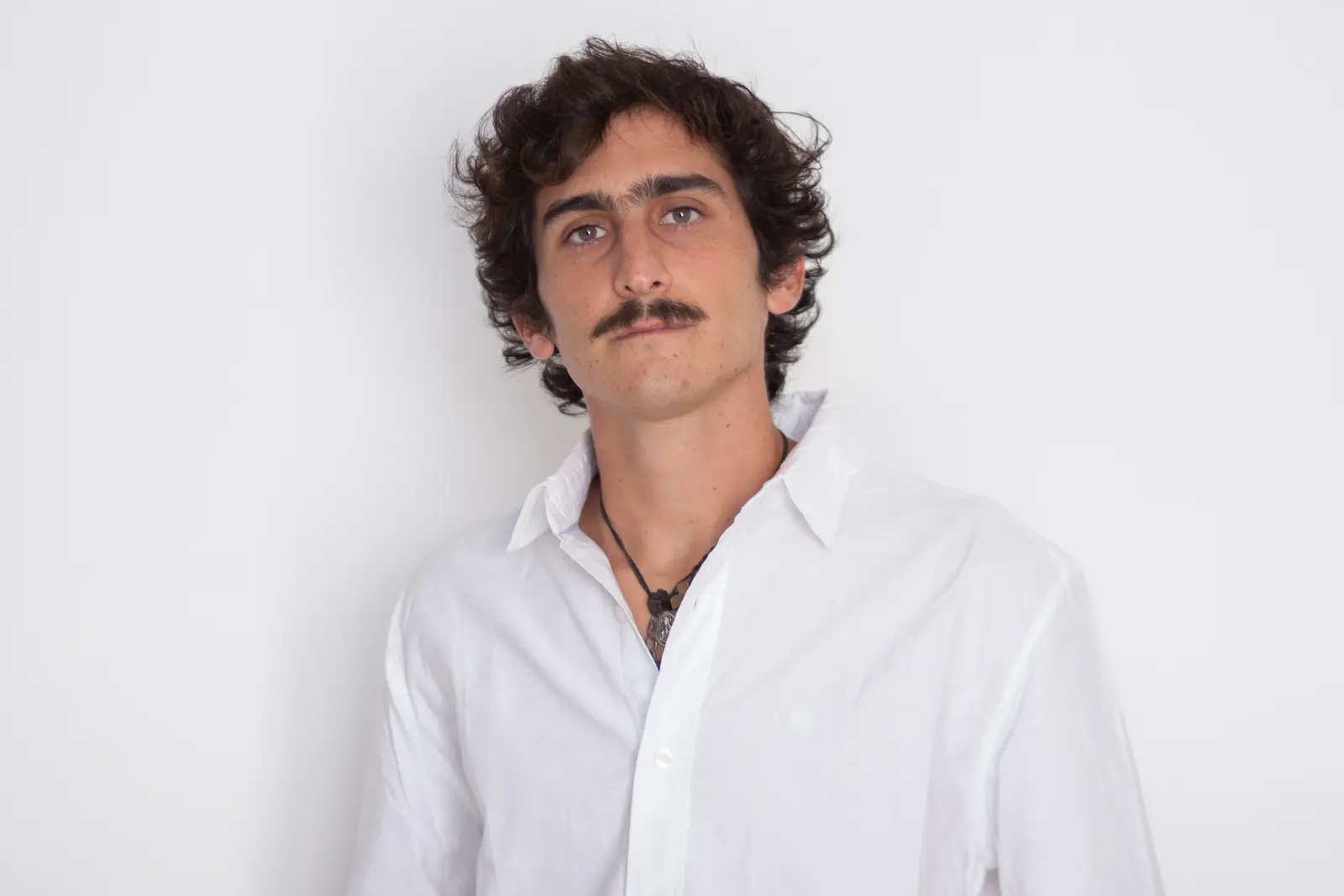 retrato de joven parado de frente vestido de blanco