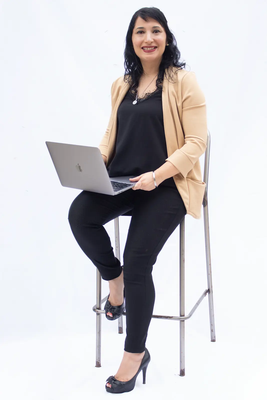 mujer con laptop sentada sobre banqueta alta y fondo blanco