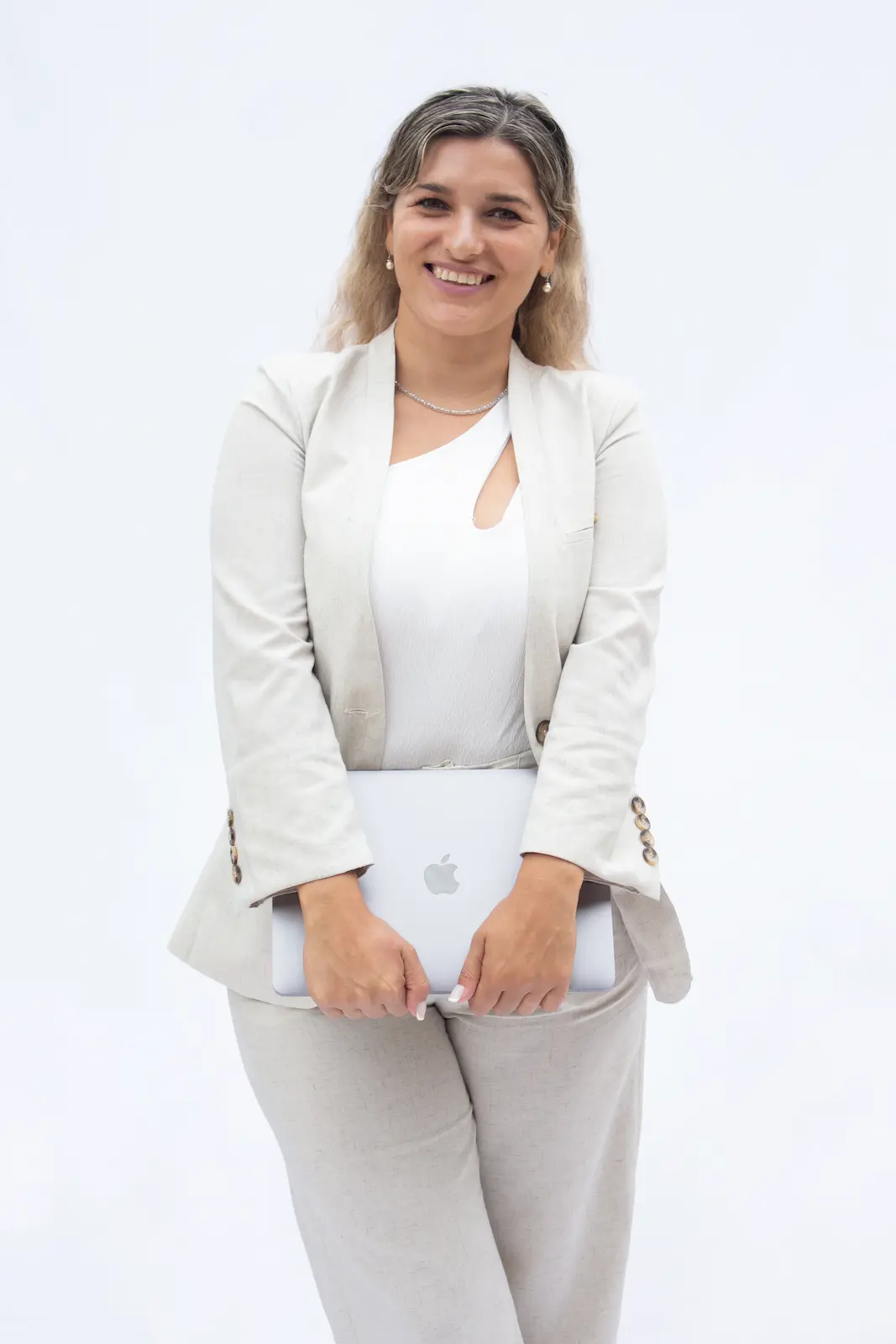 mujer parada vestida de blanco con laptop y fondo blanco