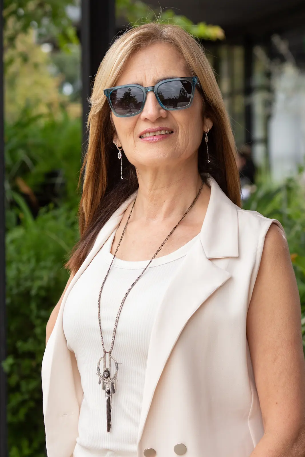 foto diurna de mujer con anteojos y ropa blanca sobre fondo natural de plantas