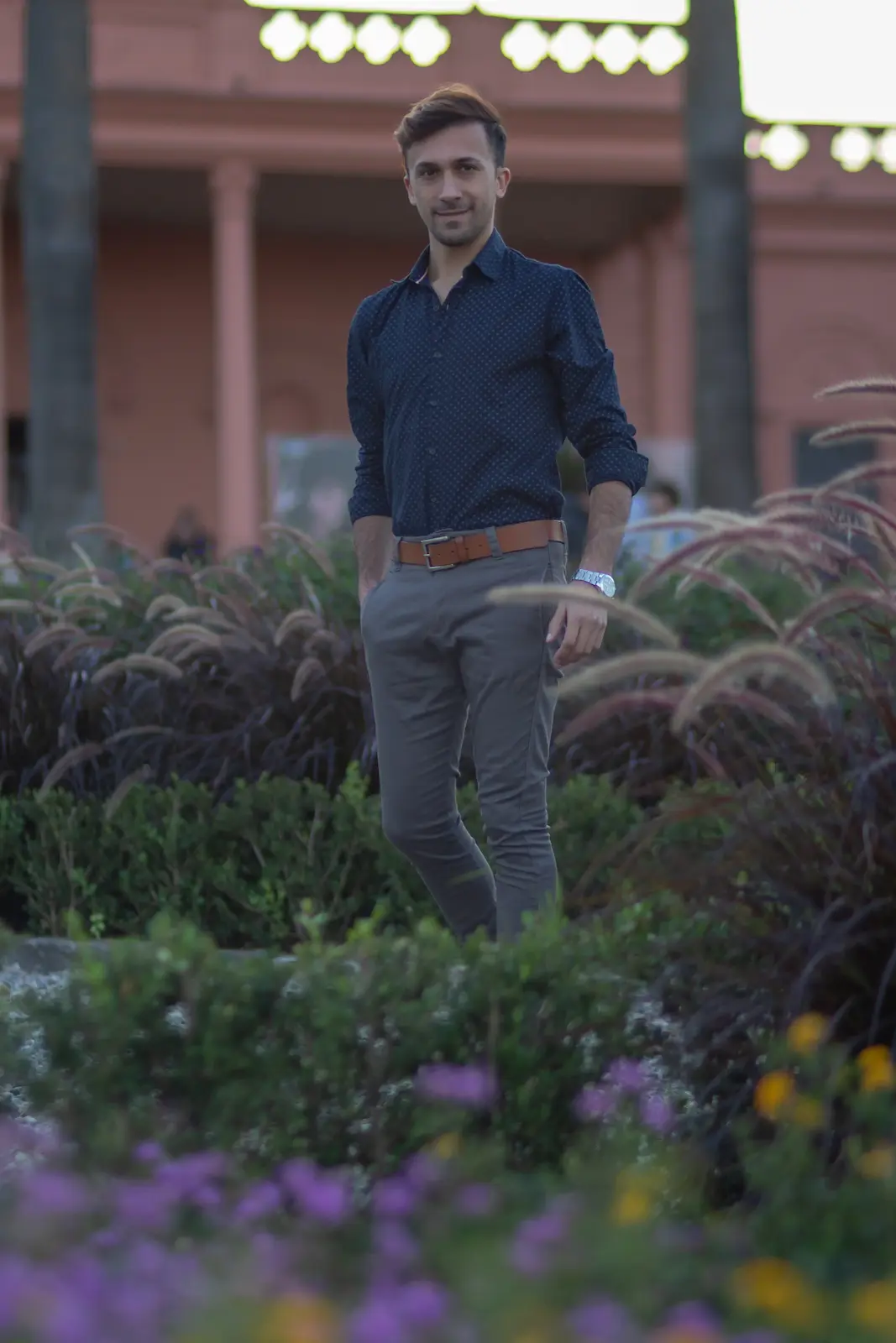 muchacho parado rodeado de jardin con plantas y casona de fondo